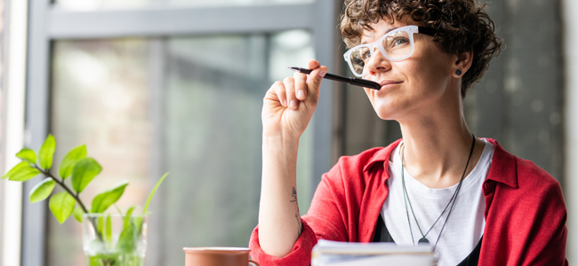 Young pensive female in eyeglasses thinking of new creative ideas